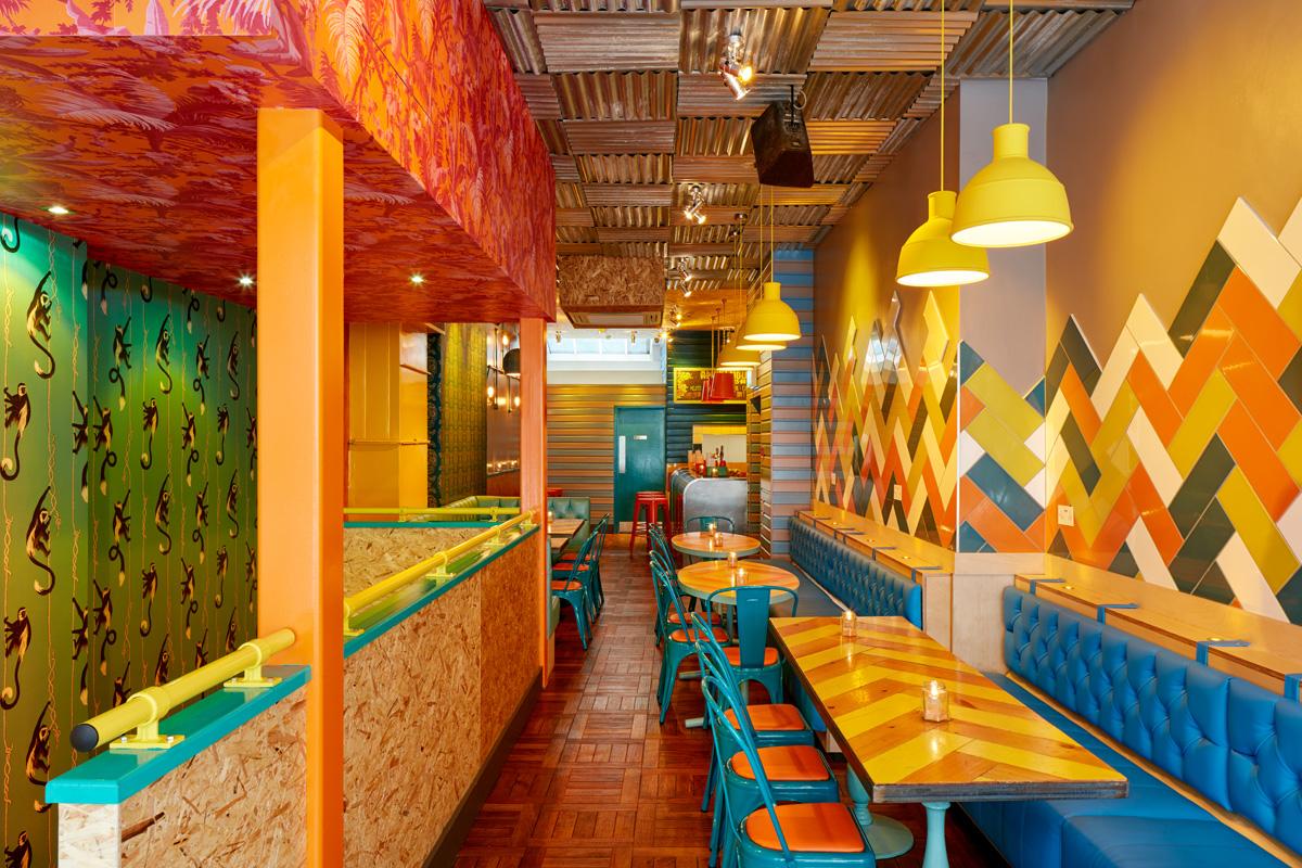 Brightly colours interiors of the ground floor seating area of Barrio in Soho. 